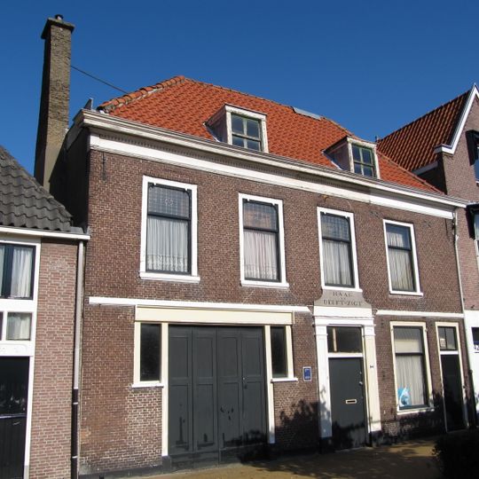 Pand met verdieping, ontstaan door samenvoeging van twee oudere huizen, waarvoor een rechthoekig woonhuis onder schilddak werd gebouwd