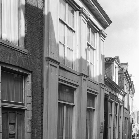 Onderkelderd pand gedekt door een met pannen belegd jonger afgeknot dwars zadeldak