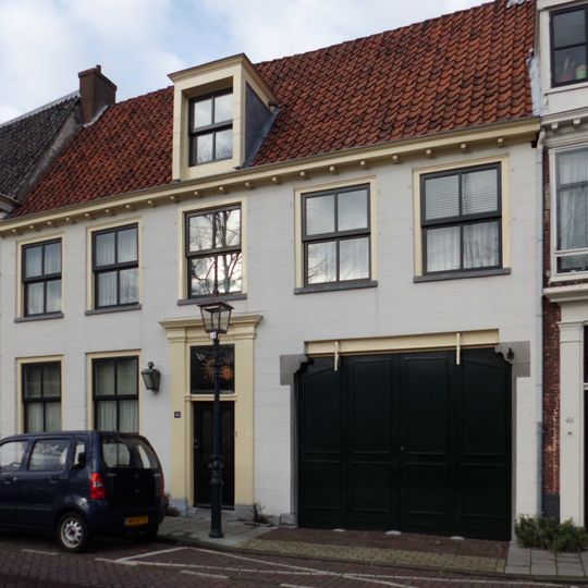 Pand met gepleisterde gevel met rechte kroonlijst onder zadeldak, deur terzijde ingebroken