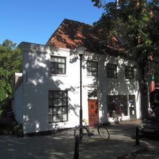 Gepleisterd pand voorgedeelte evenwijdig aan de straat, onder hoog schilddak.