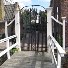 Hek naar het erf van het bouwhuis met bakstenen keermuren