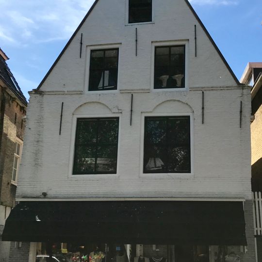 Diep pand onder zadeldak tegen topgevels, achter gepleisterd, voor deels met beitelingen