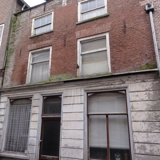 Huis met schilddak, en lijstgevel, beganegronds gebosseerd blauwgepleisterd, daarboven schoon werk, ramen met kleine roedenverdeling