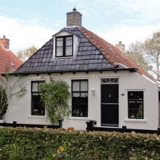 Pandje met zesruitsvensters, houten goot op blokken en gecementeerde achtergevel onder aan de voorzijde afgewolfd zadeldak