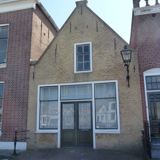 Huis met tuitgevel. Timmermanswerkplaats. Pui met middendeur