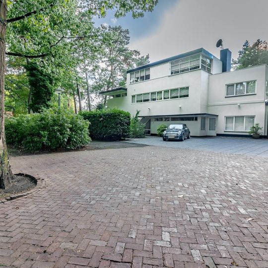 Vrijstaand, in baksteen opgetrokken, witgepleisterd, vlakgedekt woonhuis met verdieping
