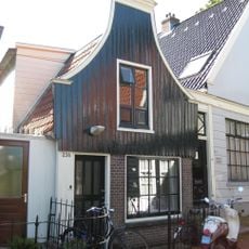 Houten huis met halsgevel (ingezwenkt voorschot) en bakstenen onderpui