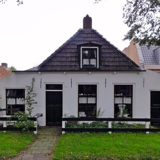 Pand met zesruitsvensters en houten goot op blokjes onder aan de voorzijde afgewolfd zadeldak