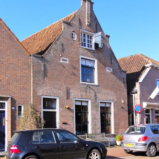 Pand met puntgevel met enkele trappen met zandstenen afdekplaten en uitgekraagde toppilaster op zandstenen kraagsteentje