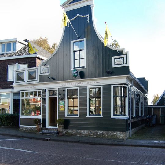 Houten huis, voorzien van een ingezwenkte voorschot met fronton, guirlande en zijmeanders