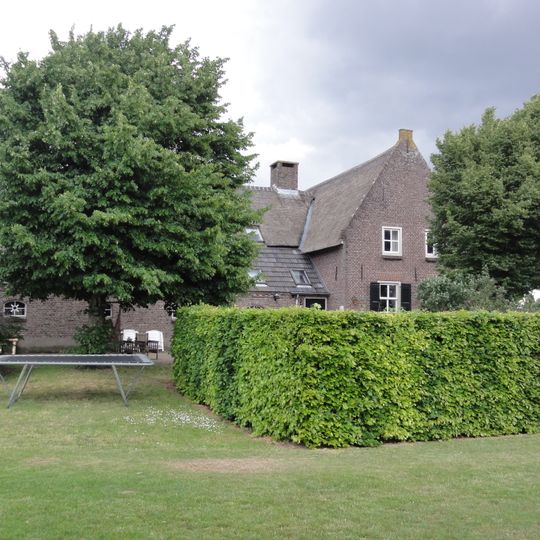 Boerderij met woongedeelte dat dwars voor de stal is gebouwd en een rieten zadeldak tussen puntgevels met vlechtingen draagt. Vensters met luiken en zesruitsschuiframen.
