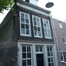 Pand met gevel met kroonlijst, die op de hoeken op bakstenen verkroppingen is omgekornist