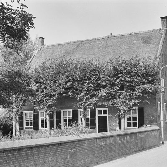 Een statige hoeve, T-huis, waarvan het rechts onderkelderde woonhuis een verdieping en een rieten zadeldak bezit