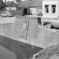 Keermuur met gebeeldhouwde gevelsteen, waarop wapen en opschrift