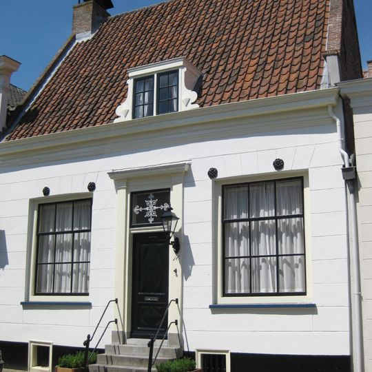 Laag huisje onder zadeldak met stoep, rechte kroonlijst, gepleisterde gevel