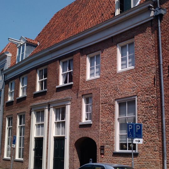 Pand met brede lijstgevel voor oud pand onder hoog dwars schilddak met twee dakkapellen met frontons en hijsbalken