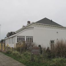 Houten saunagebouwtje op rechthoekige plattegrond, één bouwlaag hoog met aan één zijde afgewolfd zadeldak, gedekt met tuile du nord pannen