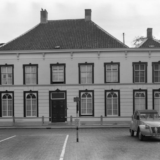 Groot pand met schilddaken en gegroefd gepleisterde lijstgevel