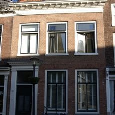 Huis met eenvoudige gevel onder zeer rijk gesneden lijst