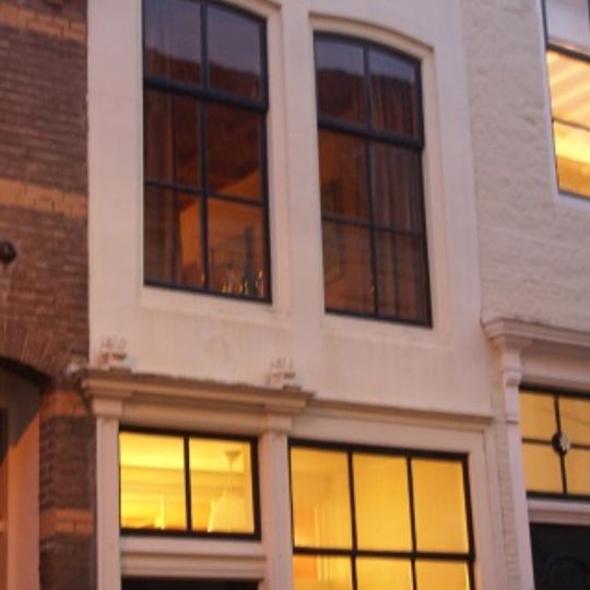 Huis met smalle gepleisterde lijstgevel en eenvoudige voordeuromlijsting