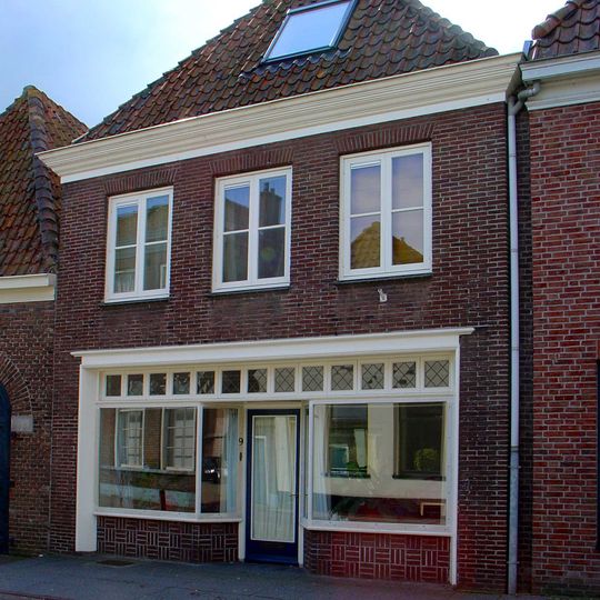 Eenvoudig pand onder aan de voorzijde afgewolfd zadeldak met jongere voorgevel