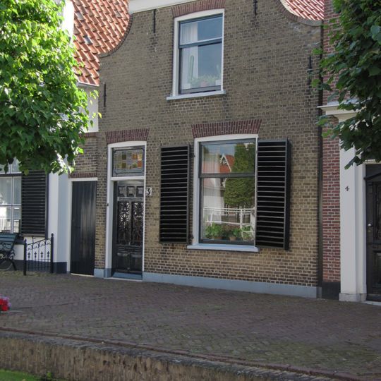 Pand met ingezwenkte gevel onder rechte lijst. IJsselsteen met rode vensterstrekken