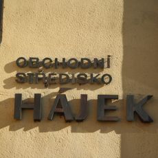 Měděný nápis Obchodní středisko Hájek na budově obchodního střediska Hájek