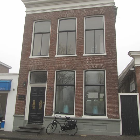 Hoog pand onder zadeldak; gevel met rechte kroonlijst en topschoorsteen met dekplaat boven voorste dakschild