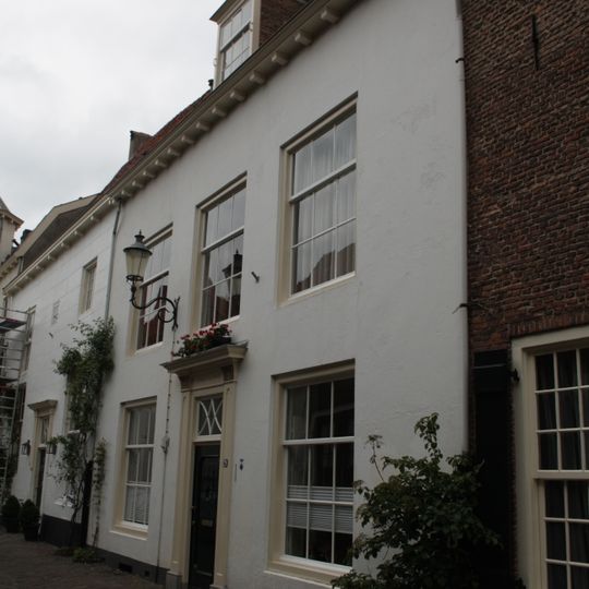 Huis met gepleisterde gevel met rechte kroonlijst. Omlijste voordeur