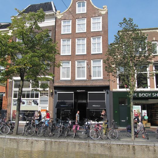 Pand met zolderverdieping onder zadeldak tegen lage klokgevel met rococo-ornament