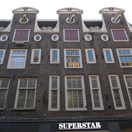 Pand met halsgevel met wapen van Amsterdam in de afdekking en twee oeils-de-boeuf. Vormt groep met nrs 100 en 102.