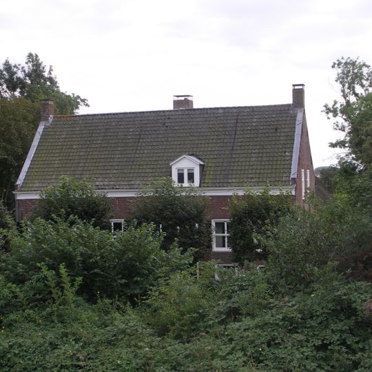 Boerderij op T-vormige plattegrond, waarvan het woongedeelte een zadeldak tussen puntgevels bezit en rechts een opkamer. Vensters met luiken en zes- en vierruitsschuiframen