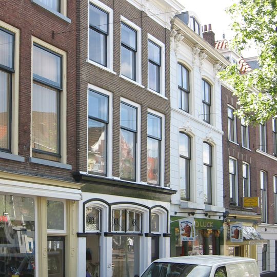 Pand onder dwars schilddak. Eenvoudige lijstgevel met viermaal verkropte, rijk gesneden kroonlijst. Op de verkroppingen gesneden Lod. XIV- consoles