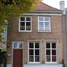 Huis onder met rode pannen belegd schilddak en met lijstgevel in schoon werk