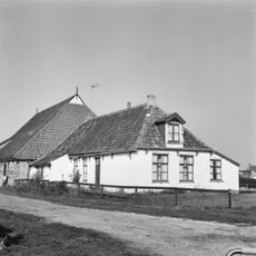 Boerderij met wit bepleisterd voorhuis onder schilddak met dakkapel en schoorsteen