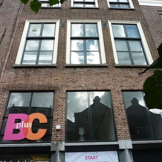 Pand met bakstenen rechte kroonlijst met barokconsoles. Onderpui verbouwd