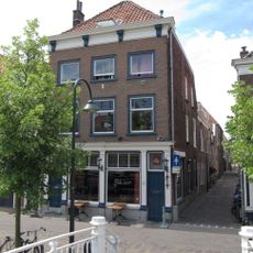 Hoekpand Vissteeg van parterre en twee verdiepingen onder hoog schilddak. Lijstgevel met gesneden Lod. XIV-consoles in de kroonlijst