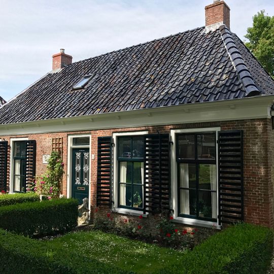 Dubbel landelijk pand met stichtingssteen en goot op klossen onder schilddak met twee hoekschoorstenen