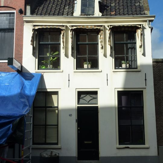 Pand met blauwgepleisterde gevel met rechte kroonlijst onder zadeldak, terzijde in topgevel eindigend met opzet