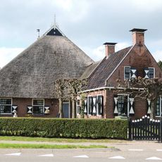 Kop-hals-rompboerderij topgevel met vlechtingen, topschoorstenen met borden en met riet gedekste schuur