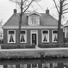 Dubbel pand onder schilddak met dakkapel en twee hoekschoorstenen