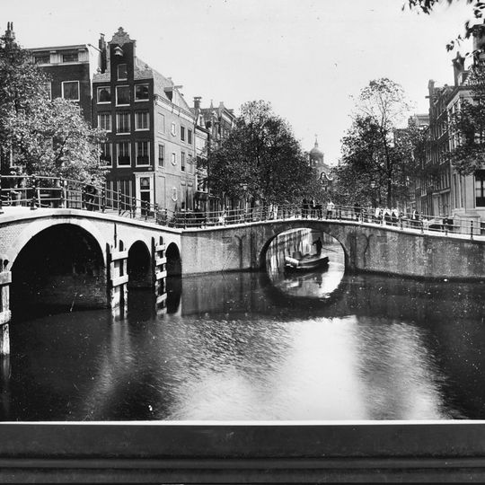 Hoekhuis met halsgevel en een deurpartij in omlijsting en met gebeeldhouwde trapvensters in- en een stoephek tegen de zijgevel