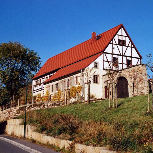 Südliches Wohnstallhaus, östliches Wohnstallhaus und nördliche Scheune eines ehem. Vierseithofes sowie Brunnen im Hof und Hofmauer mit Pforte und Tor Borna 1