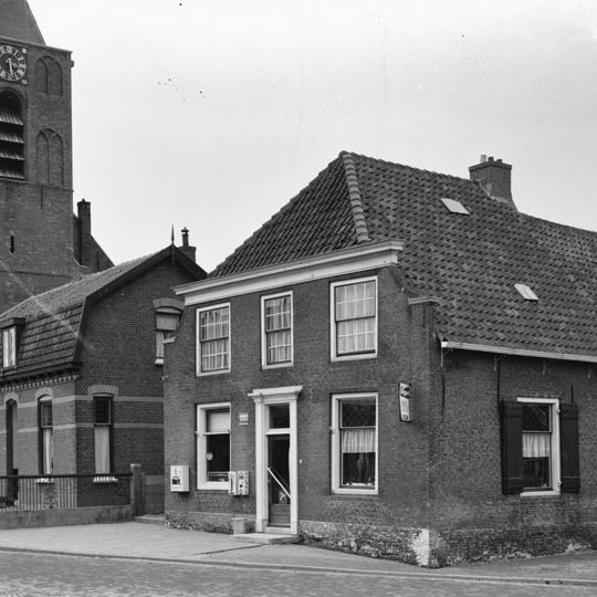 Oorspronkelijk boerderij met aan de voorzijde lijstgevel met ingezwenkte zijkanten. Zoldervensters met twintigruitsroedenverdeling in de vensters