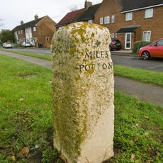 Milestone, Potton Road, in front of service road, 100m S of jct Stratton Way