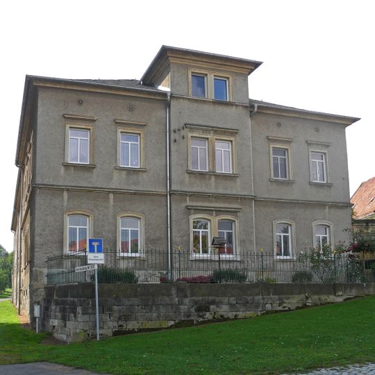 Wohnhaus, Seitengebäude und Scheune eines Bauernhofes sowie Toranlage vom Dorfplatz und rückwärtiger Torbogen an der Scheune sowie Einfriedungsmauer des Gartens südwestlich hinter der Scheune Am Rundling 7