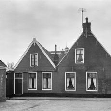 Twee panden onder zadeldak tegen puntgevel, waarvan Nije Buorren 12 met vlechtingen en aanzetlijstje