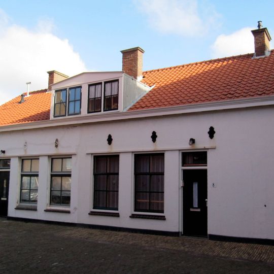 Ten dele gepleisterd pand zonder verdieping, onder met pannen gedekt zadeldak tussen puntgevels