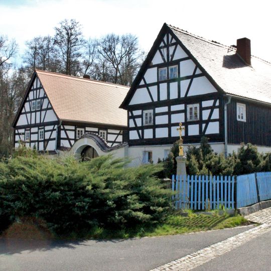 Schmiede, Wohnhaus und Torbogen eines Schmiedeanwesens sowie Betkreuz Zur Schmiede 7