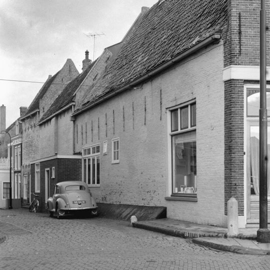 Diep pand met twee achterhuizen en brede halsgevel met aanzetkrullen en gezwenkte bekroning